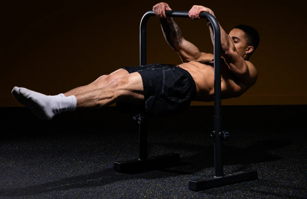 A man wearing white socks and doing a calisthenics workout, balancing himself on a black rug.