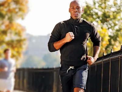 Man running on a sidewalk, starting his fitness journey as part of an introduction to fitness routine.