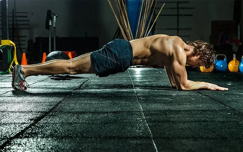 Fit man holding a plank on the ground as part of an introduction to fitness routine, highlighting core strength and endurance training.